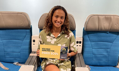Vahine Fierro sur les sièges premium d'Air Tahiti Nui qui tient une pancarte Paris 2024